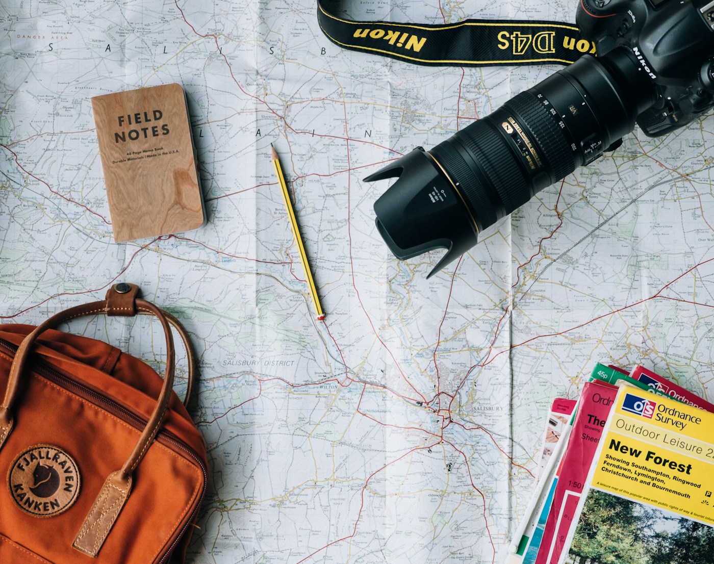 Travel planning materials and a notebook on a wooden surface.